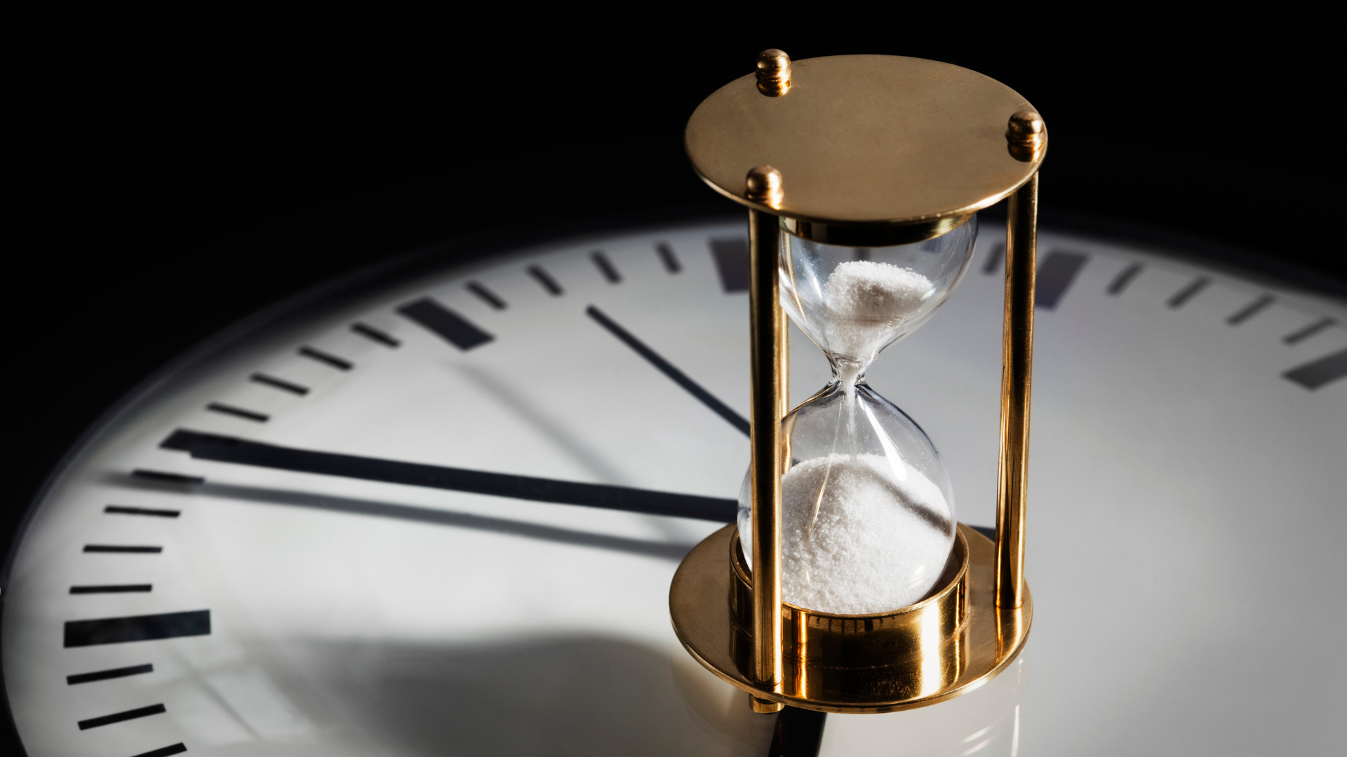 Hourglass and business icons symbolizing the timing considerations for selling a business
