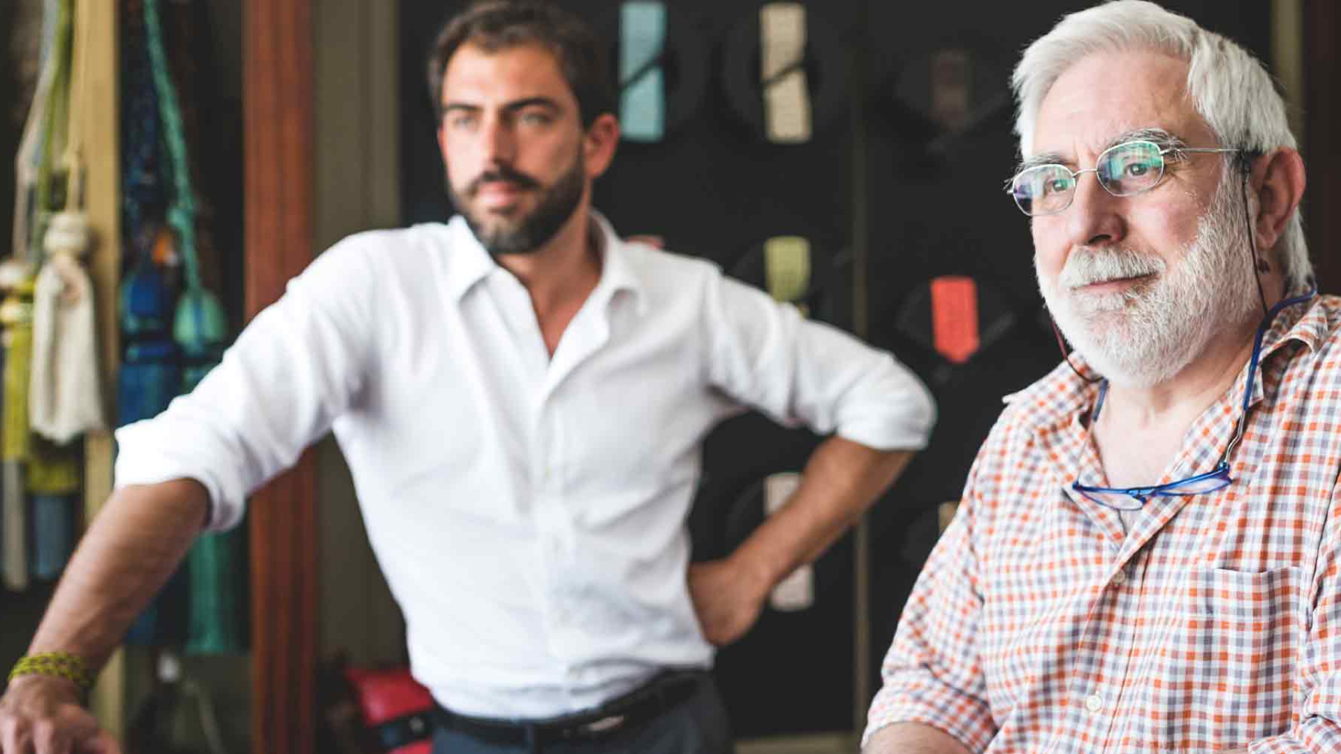 Elderly business owner with a younger man in a workshop, symbolizing the transfer of knowledge and leadership